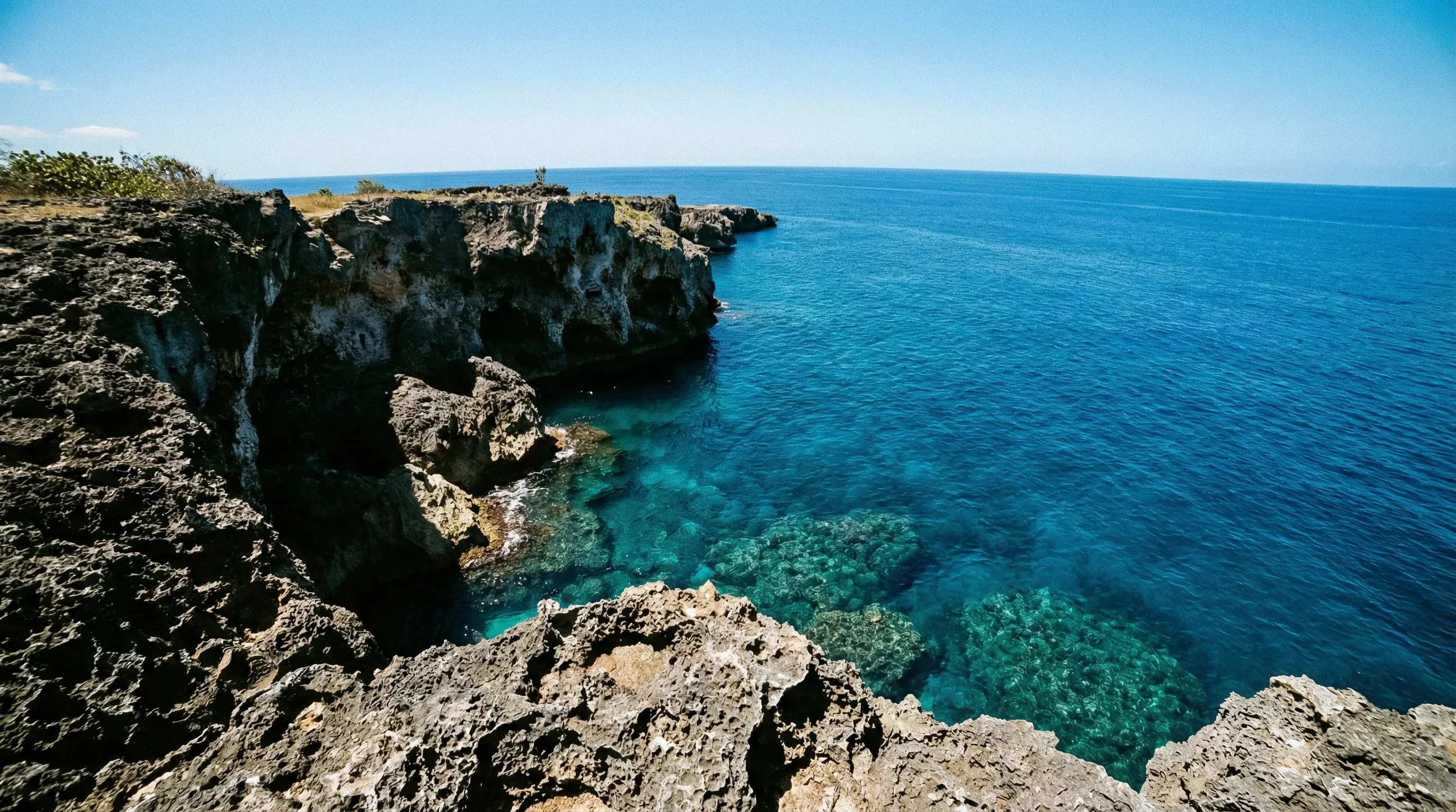 A daytime view of the rugged limestone cliffs and deep blue ocean along the West End of Negril.