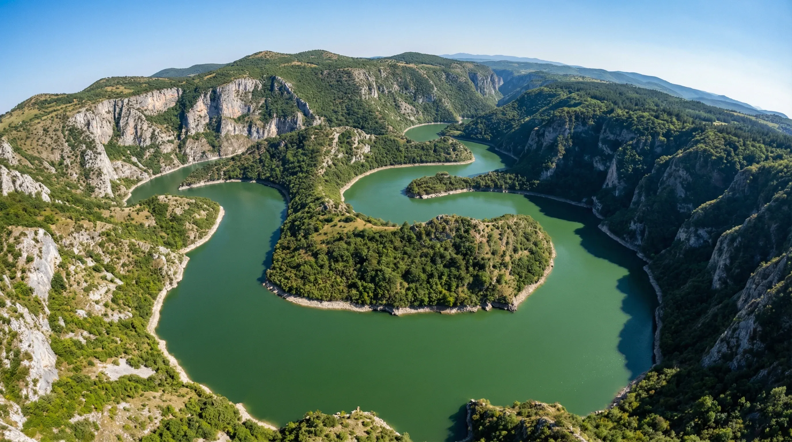 A high-angle view of the sharp green meanders of the Uvac River winding through a deep rocky canyon.